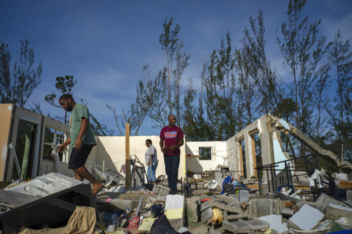 George Bolter, left, and his parents walk through the remains of his home destroyed by Hurricane Dorian in the Pine Bay neighborhood of Freeport, Bahamas, Wednesday, Sept. 4, 2019. Photo: Ramon Espinosa / AP