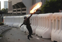Hong Kong Govt: Violence Is Harmful, Won’t Solve Divisions An anti-government protester throws a Molotov cocktail during a demonstration near Central Government Complex in Hong Kong, Sunday, Sept. 15, 2019. Police fired a water cannon and tear gas at protesters who lobbed Molotov cocktails outside the Hong Kong government office complex Sunday, as violence flared anew after thousands of pro-democracy supporters marched through downtown in defiance of a police ban. Photo: Kin Cheung / AP
