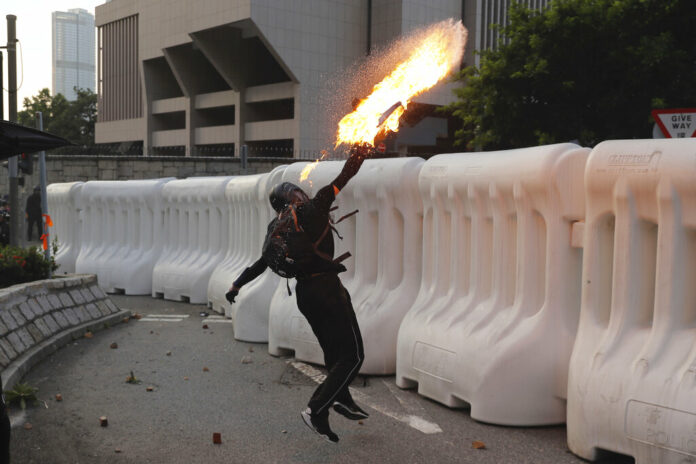 An anti-government protester throws a Molotov cocktail during a demonstration near Central Government Complex in Hong Kong, Sunday, Sept. 15, 2019. Police fired a water cannon and tear gas at protesters who lobbed Molotov cocktails outside the Hong Kong government office complex Sunday, as violence flared anew after thousands of pro-democracy supporters marched through downtown in defiance of a police ban. Photo: Kin Cheung / AP