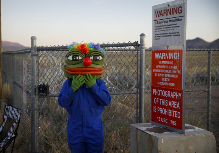 Martin Custodio wears a Pepe mask while standing near razor wire at an entrance to the Nevada Test and Training Range near Area 51, Friday, Sept. 20, 2019, near Rachel, Nev. People came to visit the gate inspired by the 