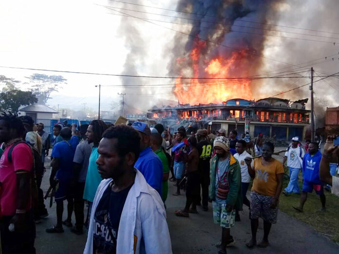 People gather as shops burn in the background during a protest in Wamena in Papua province, Indonesia, Monday, Sept 23, 2019. Hundreds of protesters in Indonesia's restive Papua province set fire to homes and other buildings Monday in a protest sparked by rumors that a teacher had insulted students, and a soldier was killed in another protest in the region, police said. Photo: AP