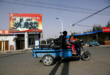 US Steps up Pressure on China Over Treatment of Muslims FILE - In this Sept. 20, 2018, file photo, an Uighur woman shuttles school children on an electric scooter as they ride past a propaganda poster showing China's President Xi Jinping joining hands with a group of Uighur elders in Hotan, in western China's Xinjiang region. The Trump administration, locked in a trade war with China, is increasing the pressure on Beijing over what it says is the systematic oppression of ethnic minority Muslims. American officials hosted a panel Tuesday, Sept. 24, 2019, on the sidelines of the United Nations General Assembly gathering in New York to highlight the plight of Uighurs, whose native land in China’s far western Xinjiang province they say is a police state. Photo: Andy Wong / AP File