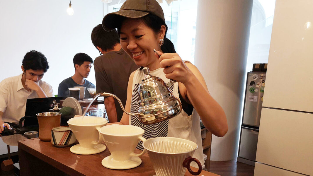 A barista pouring boiling water onto grounded coffee beans.