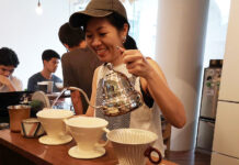 The Bangkok Drip Coffee Shop Where Caffeine Meets Meditation A barista pouring boiling water onto grounded coffee beans.