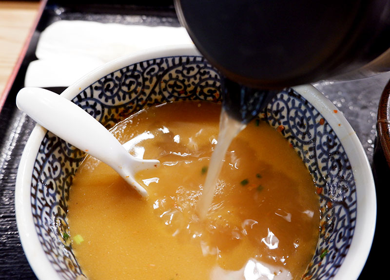 Pouring stock into tsukemen dipping sauce.