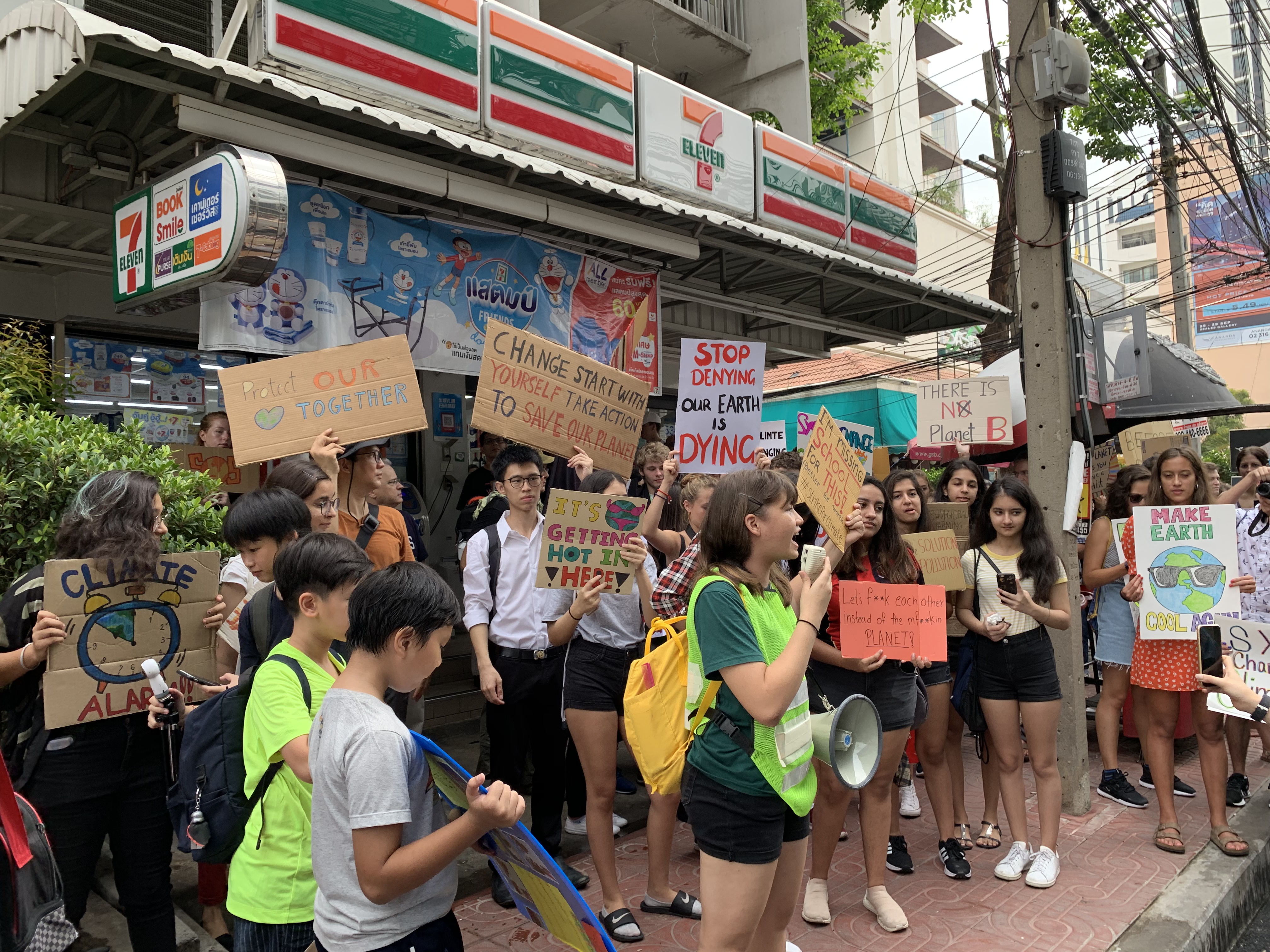 Marlena Wilson speaking in front of a 7-Eleven store on Phahonyothin Soi 7.