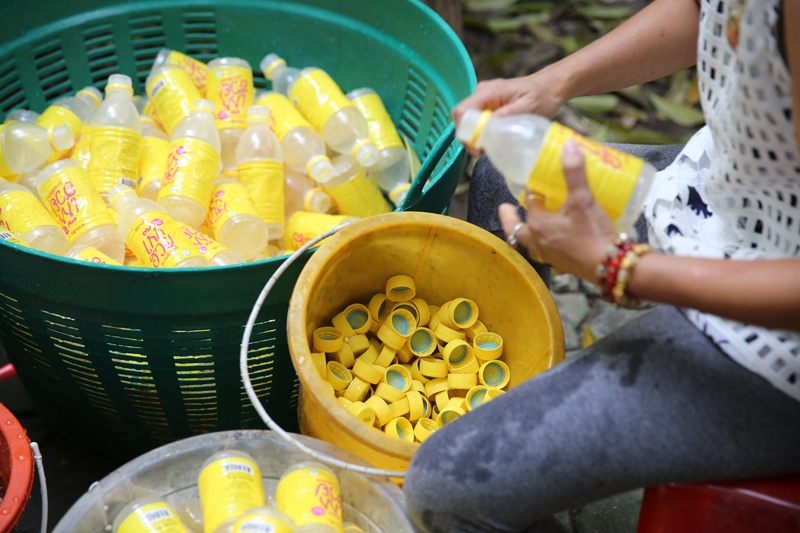 Volunteers sorting plastic bottles by removing lids, which are made of high density polyethylene (HTPE), from bottles made of polyethylene terephthalate (PET).