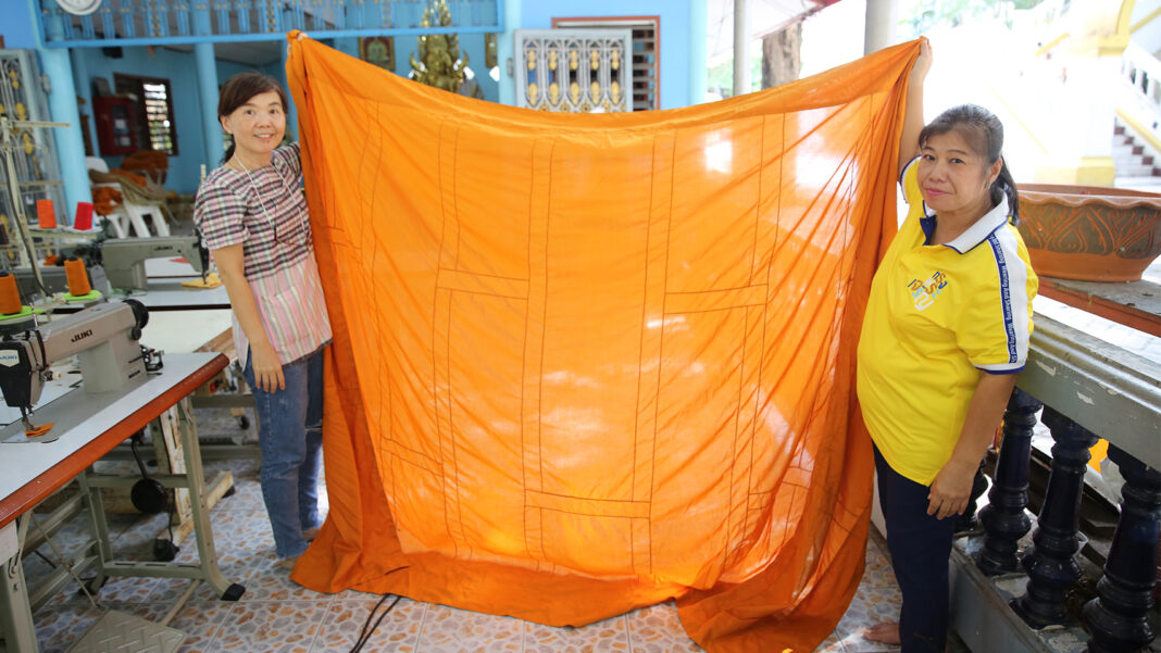 Volunteers showing a piece of robe made from recycled fibers.