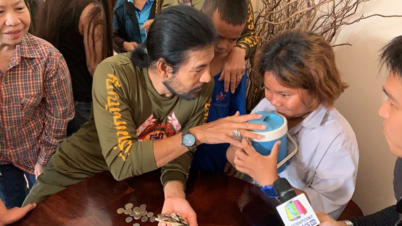 Bin Banluerit accepts a donation of 321 baht from Supatchara Kemnangrong, 11, on Sept. 19, 2019, which she had collected in her piggy bank for him.