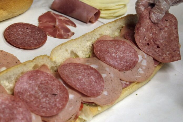 In this June 5, 2014, file photo, a man makes a submarine sandwich with mortadella, cooked salami, ham, Genoa salami and sweet capicola at a delicatessen in Massachusetts. (AP Photo/Elise Amendola, File)