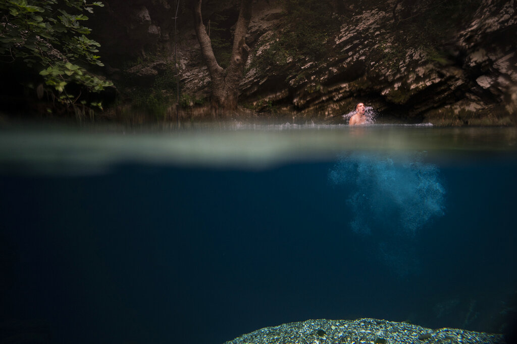 In this June 24, 2019 photo, a man jumps into a spring where it meets the Vjosa River in the Kelcyre Gorge, Albania. Albania’s government has set in motion plans to dam the Vjosa and its tributaries to generate much-needed electricity for one of Europe’s poorest countries, with the intent to build eight dams along the main river. Phot:o: Felipe Dana / AP