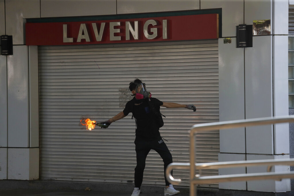 A protester throws a Molotov cocktail at a police station in Hong Kong, Sunday, Oct. 20, 2019. Hong Kong protesters again flooded streets on Sunday, ignoring a police ban on the rally and demanding the government meet their demands for accountability and political rights. Photo: Kin Cheung / AP