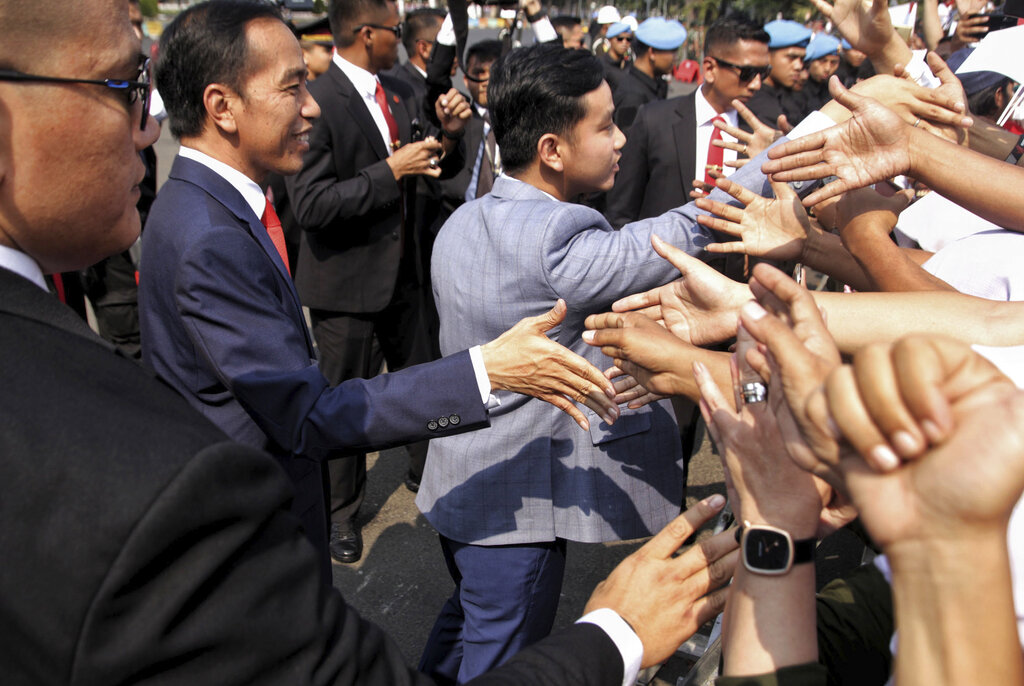Indonesian President Joko Widodo, left, and his son, Gibran Rakabuming Raka, center, greet supporters prior to the inauguration for his second term, in Jakarta, Indonesia, Sunday, Oct. 20, 2019. Indonesian President Joko Widodo, who rose from poverty and pledged to champion democracy, fight entrenched corruption and modernize the world's most populous Muslim-majority nation, was sworn in Sunday for his second and final five-year term with a pledge to take bolder actions. Photo: AP