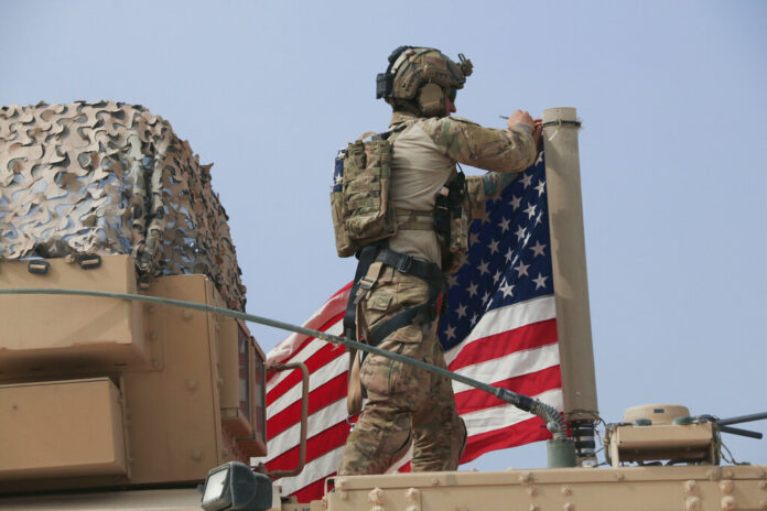 American soldier mount the U.S. flag on a vehicle near the town of Tel Tamr, north Syria, Sunday, Oct. 20, 2019. Kurdish-led fighters and Turkish-backed forces clashed sporadically Sunday in northeastern Syria amid efforts to work out a Kurdish evacuation from a besieged border town, the first pull-back under the terms of a U.S.-brokered cease-fire. Photo: Baderkhan Ahmad / AP