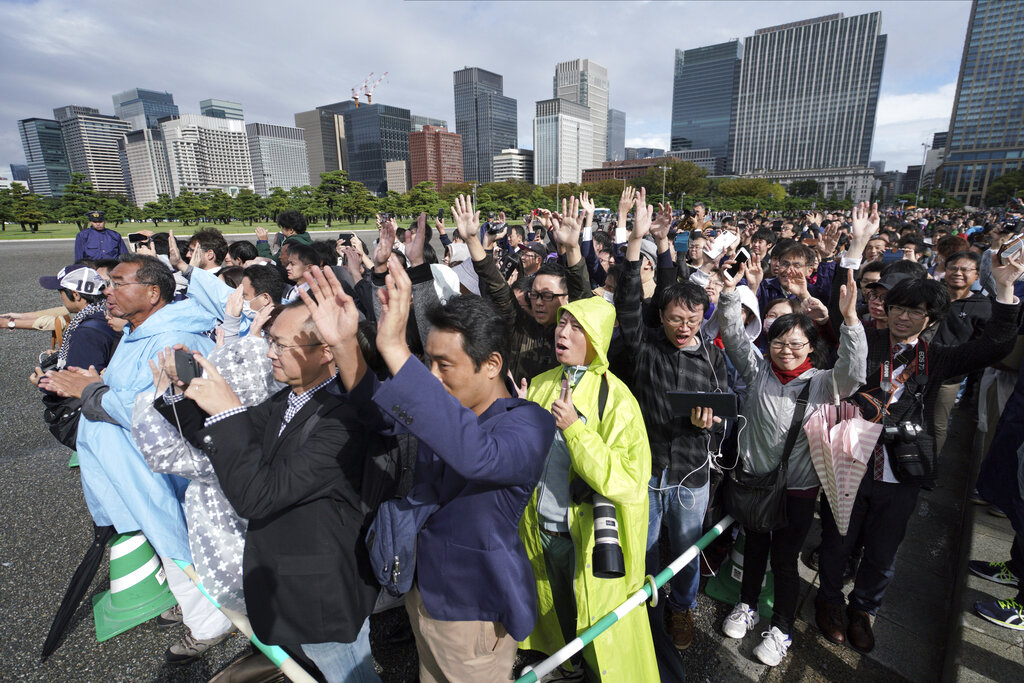 People outside of the Tokyo Imperial Palace follow Prime Minister Shinzo Abe's three "banzai" cheers for the 59-year-old Emperor Naruhito during the enthronement ceremony, Tuesday, Oct. 22, 2019, in Tokyo, Japan. Photo: Eugene Hoshiko / AP
