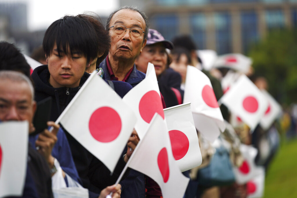 Holding nationals flags, people line up and wait outside of the Imperial Palace during the enthronement ceremony for Emperor Naruhito Tuesday, Oct. 22, 2019, in Tokyo. Photo: Eugene Hoshiko / AP