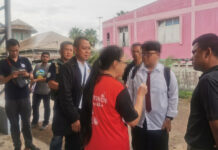 Man Arrested for Hacking Gov’t Cash Giveaway Website Thiranat Mahatthanobol, standing to the right of his mother in red shirt, during a police raid at his home in Pattani on Oct. 28, 2019.