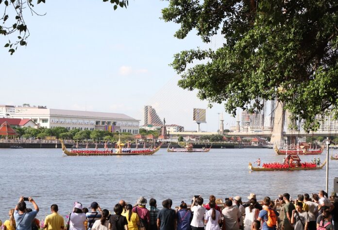 A crowd observes a rehearsal of the royal barge procession from Santi Chaiprakan Park in Bangkok on Oct. 17, 2019.