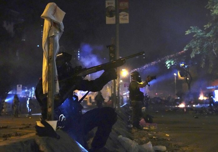 Police in riot gear prepare to fire as they move into the campus of Hong Kong Polytechnic University in Hong Kong, early Monday, Nov. 18, 2019. (AP Photo/Vincent Yu)