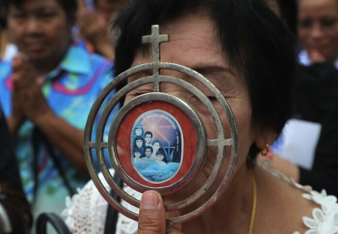 In this Saturday, Oct. 19, 2019, photo, a Catholic devotee kisses a sacramental with an image of the seven martyrs at cemetery during the 30th anniversary of the beatification of seven martyrs at Songkhon in Mukdahan province, northeastern of Thailand. (AP Photo/Sakchai Lalit)