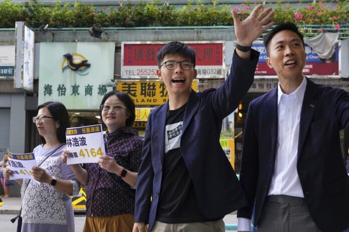 Election winner candidate Kelvin Lam, right, and pro-democracy activist Joshua Wong, second right, wave to people and thank for their support, outside South Horizons Station in Hong Kong, Monday, Nov. 25, 2019. (AP Photo/Vincent Yu)