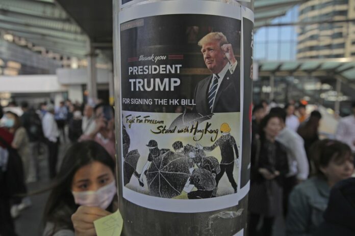 Protesters sticks a poster featuring U.S. President Donald Trump on a pillar during a demonstration in Central, the financial district of Hong Kong, Thursday, Nov. 28, 2019. (AP Photo/Kin Cheung)