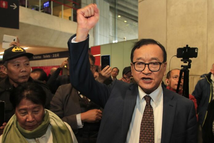 Cambodia's most prominent opposition politician Sam Rainsy clenches his fist as he is attempting to return to Cambodia Thursday, Nov. 7, 2019 at Charles de Gaulle airport, north of Paris. (AP Photo/Michel Euler)