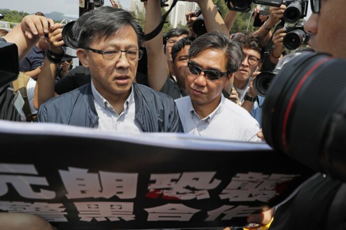In this Aug. 12, 2019, photo, pro-Beijing lawmaker Junius Ho, left, attends a demonstration of an anti-riot vehicle equipped with water cannon at the Police Tactical Unit Headquarters in Hong Kong. (AP Photo/Kin Cheung)