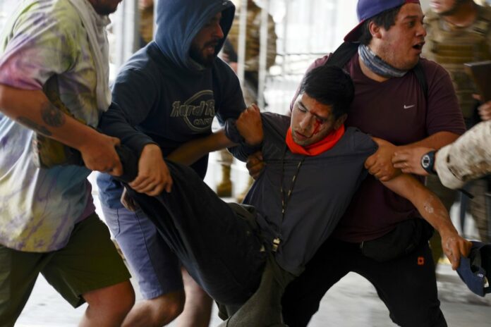 In this Oct. 25, 2019 file photo, an anti-government protester is carried away after being injured during clashes with police in Valparaiso, Chile. (AP Photo/Matias Delacroix, File)