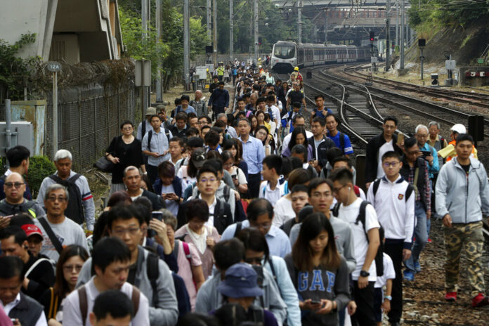 Commuters walk on the railway after their train service is disrupted by pro-democracy protesters in Hong Kong, Tuesday, Nov. 12, 2019. Protesters disrupted the morning commute in Hong Kong on Tuesday after an especially violent day in the Chinese city that has been wracked by anti-government protests for more than five months. Photo: AP