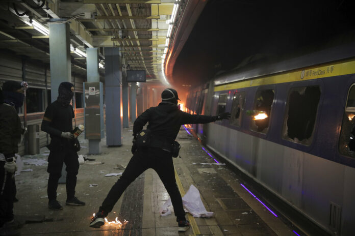 A student hurls a molotov cocktail into a train parked inside the Chinese University MTR station in Hong Kong, Wednesday, Nov. 13, 2019. Protesters in Hong Kong battled police on multiple fronts on Tuesday, from major disruptions during the morning rush hour to a late-night standoff at a prominent university, as the 5-month-old anti-government movement takes an increasingly violent turn. Photo: Kin Cheung / AP