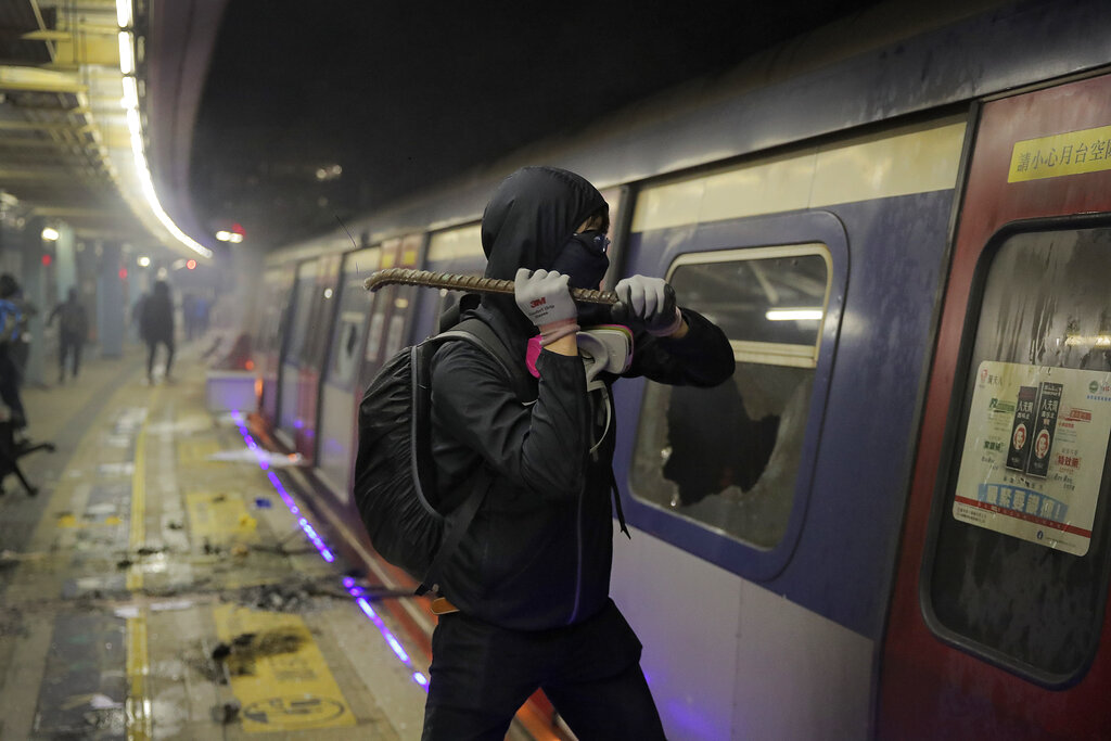 A student vandalizes a train parked inside the Chinese University MTR station in Hong Kong, Wednesday, Nov. 13, 2019. Protesters in Hong Kong battled police on multiple fronts on Tuesday, from major disruptions during the morning rush hour to a late-night standoff at a prominent university, as the 5-month-old anti-government movement takes an increasingly violent turn. Photo: Kin Cheung / AP