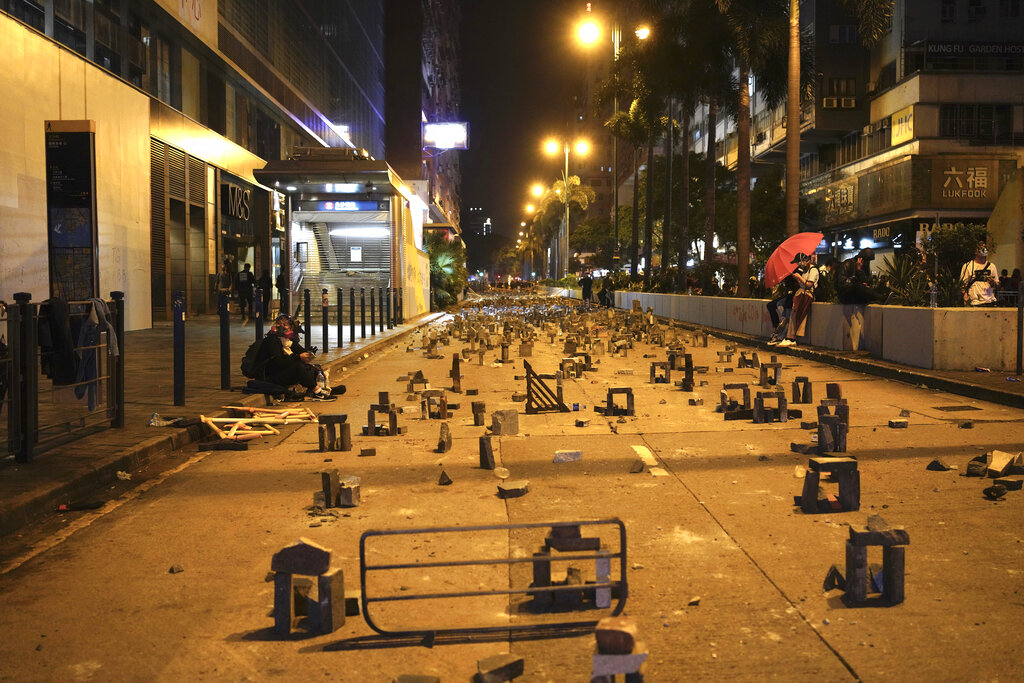 Protestors rest near a road barricaded with bricks in Hong Kong, early Tuesday, Nov. 19, 2019. About 100 anti-government protesters remained holed up at a Hong Kong university Tuesday as a police siege of the campus entered its third day. Photo: Vincent Yu / AP