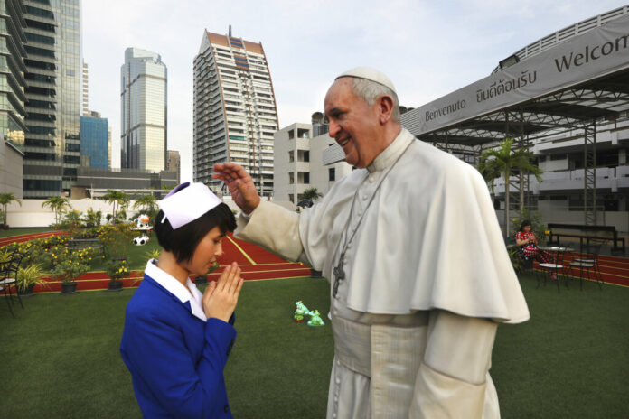 A nurse bows to the life size statue of Pope Francis as her friend takes a photograph at the St.Louis hospital in Bangkok, Thailand, Tuesday, Nov. 19, 2019. Pope Francis arrives in Thailand on Wednesday for the first visit here by the head of the Roman Catholic Church since St. John Paul II in 1984. Photo: Manish Swarup / AP