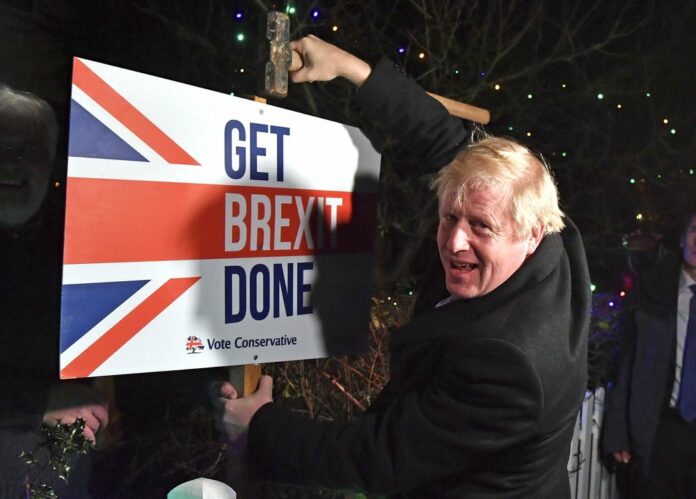 Britain's Prime Minister and Conservative party leader Boris Johnson poses as he hammers a