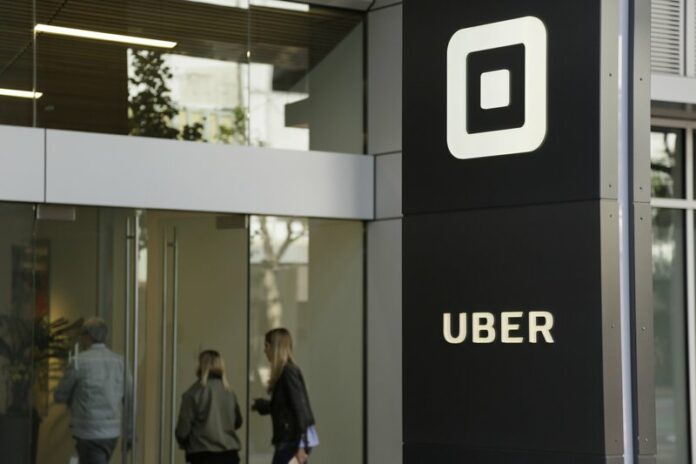 In this June 21, 2017, file photo, people make their way into the building that houses the headquarters of Uber in San Francisco.