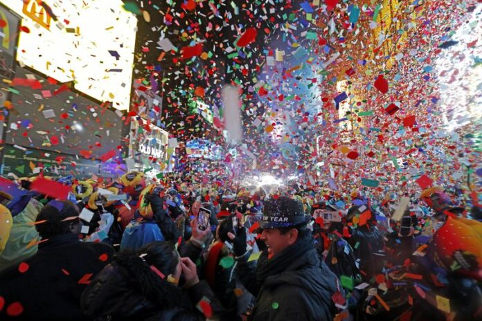 In this Tuesday, Jan. 1, 2019, file photo, Joey Flores, of California, uses his cellphone as confetti falls during a New Year's celebration in New York's Times Square. (AP Photo/Adam Hunger, File)