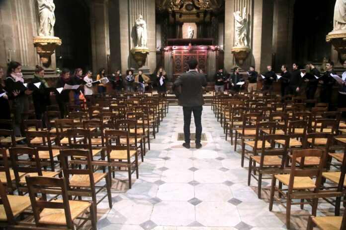 In this photo taken Monday, Dec. 16, 2019, Notre Dame cathedral choir's director Henri Chalet directs the Notre Dame choir during a rehearsal at the Saint Sulpice church in Paris. (AP Photo/Michel Euler)