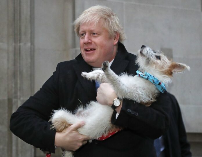 Britain's Prime Minister and Conservative Party leader Boris Johnson holds his dog Dilyn as he leaves after voting in the general election at Methodist Central Hall, Westminster, London, Thursday, Dec. 12, 2019. (AP Photo/Frank Augstein)