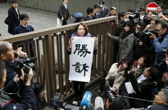 Shiori Ito holds a banner reading