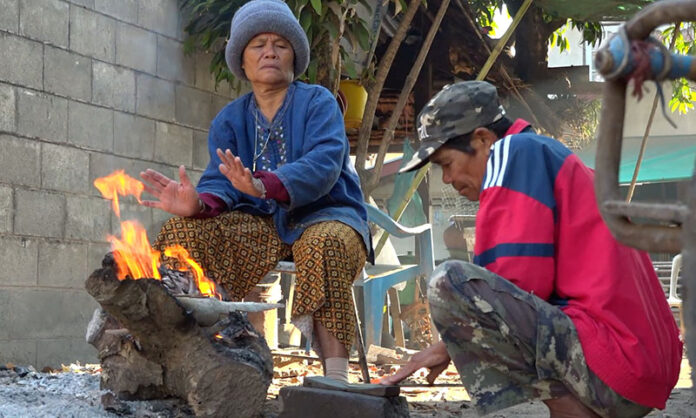Locals in Kranuan district, Khon Kaen, gather around a campfire to keep warm from the cold on Dec. 3, 2019.