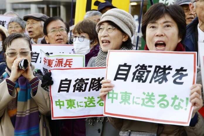 Protesters hold placards reading