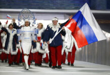 World Anti-Doping Agency Imposes 4-Year Ban on Russia In this Feb. 7, 2014 file photo Alexander Zubkov of Russia carries the national flag as he leads the team during the opening ceremony of the 2014 Winter Olympics in Sochi, Russia. at left is model Irina Shayk carrying the Russian placard. Photo: Mark Humphrey / AP