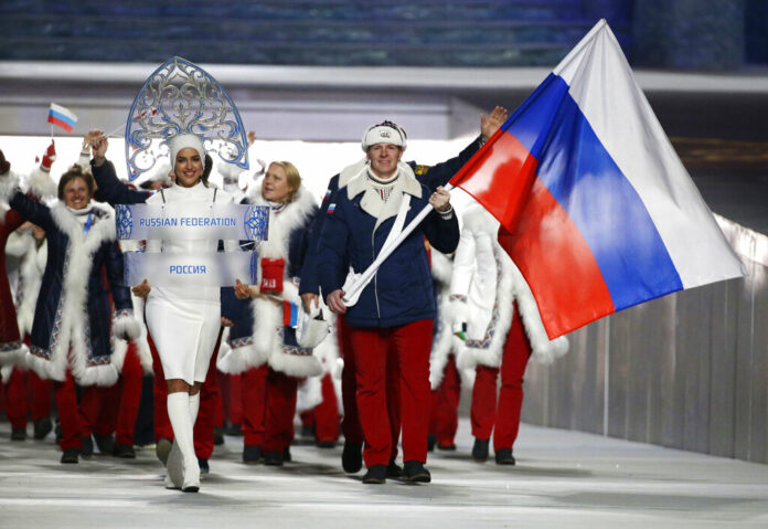 In this Feb. 7, 2014 file photo Alexander Zubkov of Russia carries the national flag as he leads the team during the opening ceremony of the 2014 Winter Olympics in Sochi, Russia. at left is model Irina Shayk carrying the Russian placard. Photo: Mark Humphrey / AP