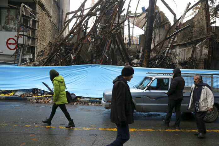 In this Nov. 20, 2019, file photo, people walk past buildings that were burned during recent protests, in Shahriar, Iran, some 40 kilometers (25 miles) southwest of the capital, Tehran. Amnesty International says at least 208 people in Iran have been killed amid protests over sharply rising gasoline prices and a subsequent crackdown by security forces. The country has yet to release any nationwide statistics about the unrest last month. Photo: Vahid Salemi, File / AP