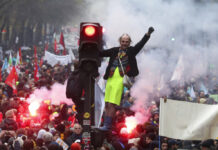 Paris Police Arrest Scores Amid Strike Over Pension Reform A man stands on a traffic light during a demonstration in Paris, Thursday, Dec. 5, 2019. The Eiffel Tower shut down, France's vaunted high-speed trains stood still and several thousand protesters marched through Paris as unions launched open-ended, nationwide strikes Thursday over the government's plan to overhaul the retirement system. Photo: Thibault Camus / AP