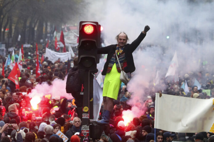 A man stands on a traffic light during a demonstration in Paris, Thursday, Dec. 5, 2019. The Eiffel Tower shut down, France's vaunted high-speed trains stood still and several thousand protesters marched through Paris as unions launched open-ended, nationwide strikes Thursday over the government's plan to overhaul the retirement system. Photo: Thibault Camus / AP