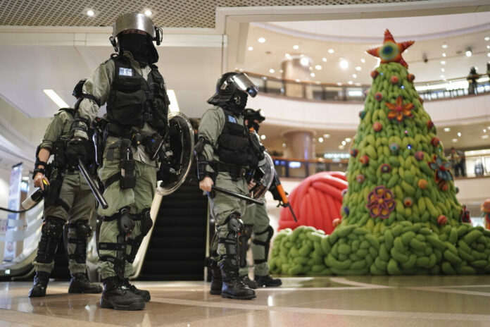 Riot police past by a Christmas decor in a mall during a protest rally on Christmas Eve in Hong Kong on Tuesday, Dec. 24, 2019. More than six months of protests have beset the city with frequent confrontations between protesters and police. Photo: Kin Cheung / AP