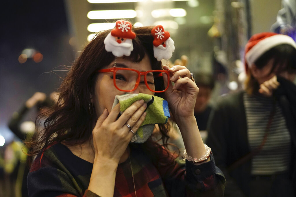 A woman wearing Christmas decorations in her hair reacts to tear gas as police confront protesters on Christmas Eve in Hong Kong on Tuesday, Dec. 24, 2019. More than six months of protests have beset the city with frequent confrontations between protesters and police. Photo: Kin Cheung / AP