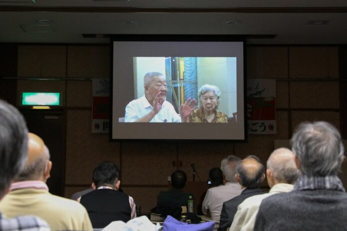 Ge Daorong, a survivor of the Nanjing Massacre (on the left side of the video screen) is seen in a video shown at a testimony meeting to convey the truth about the Nanjing Massacre, in Tokyo, Japan, Dec. 11, 2019. (Xinhua/Du Xiaoyi)